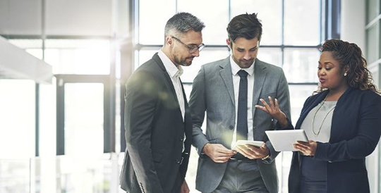 Three people talking and looking at paperwork