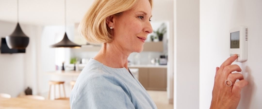 a woman adjusting her home's thermostat